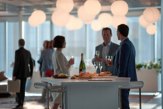 Business networking event with champagne and appetizers. Blurred professionals mingling at a corporate party reception