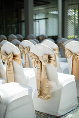 Vertical view of wedding chairs with beautiful gold satin bows
