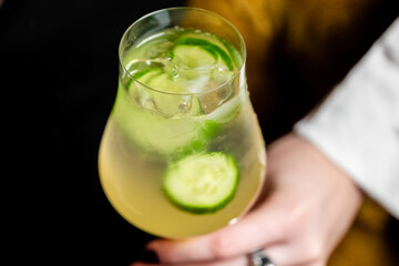A refreshing cucumber and lime cocktail or spritzer with ice, held in a wine glass. Perfect for summer drinks, healthy recipes, and beverage photography