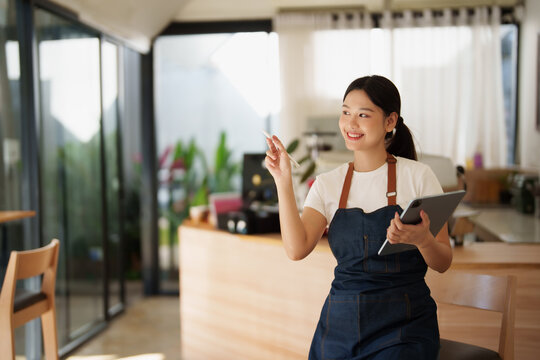 Asian woman barista managing coffee shop looking away