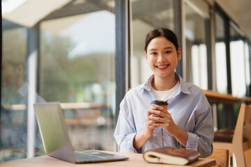 Obraz premium Young woman enjoying coffee while working remotely at cafe