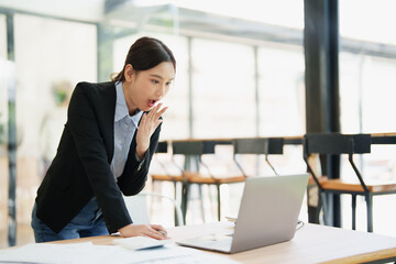 Young Asian businesswoman reacting with surprise to news on laptop