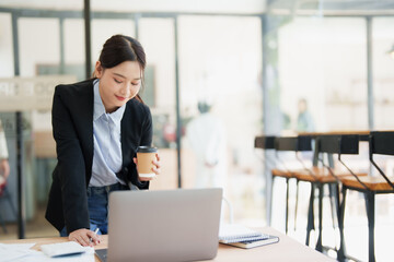 Asian businesswoman analyzing data on laptop at office