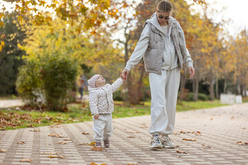A beautiful woman walks in the park with a child 