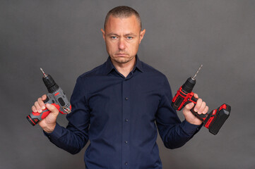 man holds two cordless screwdrivers, demonstrating the tools' ergonomic design and functionality. modern power tools ready for various DIY projects or professional tasks. on grey background