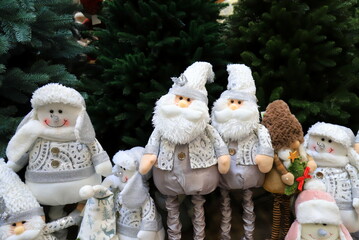 Christmas and New Year toys and decorations. Funny beautiful gnomes, snowmen, dolls under Christmas tree. Festive winter fair, sale in shopping center.