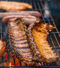 Close-Up of Juicy Pork Spare Ribs and Sausages Grilling on a Barbecue Rack over Hot Coals