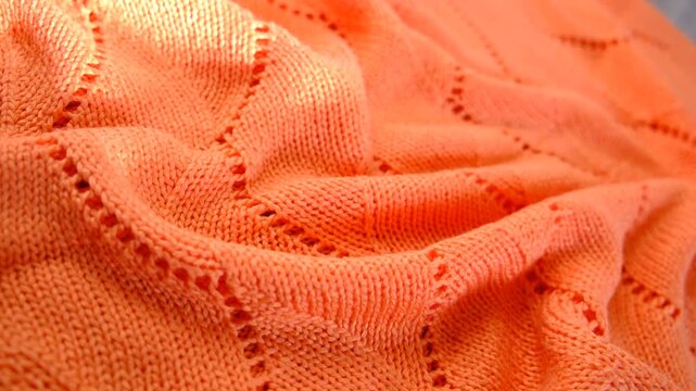 Coral color knitted fabric texture, mercerized. Product from wool. Handwork , Folded in waves and folds textiles, close up fabric. Detailed warm yarn background. Cardigan, sweater