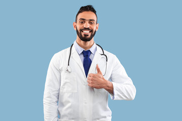 A male doctor in a white coat smiles confidently while giving a thumbs-up gesture. He is wearing a tie and stethoscope, set against a blue background.
