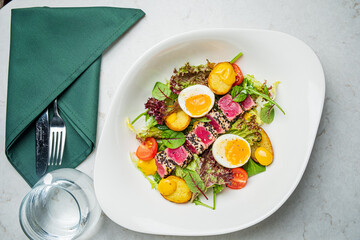 A vibrant plate of salad with greens, perfectly cooked poached eggs, and sweet cherry tomatoes