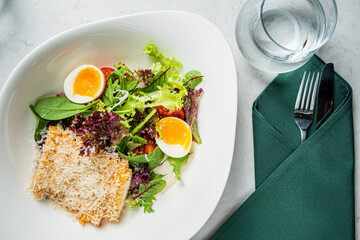 A colorful salad features fresh greens and soft-boiled eggs, served elegantly in a modern cafe