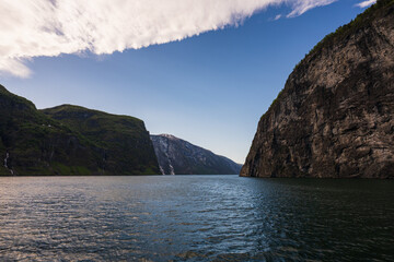 Majestic Scenic Landscape of a Norwegian Fjord with Towering Rocky Cliffs and Deep Blue Water Under a Dramatic Cloudy Sky