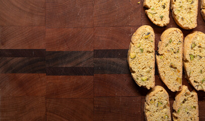 Batch of prange and pistachio, freshly baked biscotti on a wooden cutting board with copy space