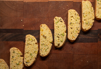 Diagonal line of freshly baked biscotti cookies on a cutting board with crumbs and copy space