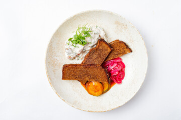 A delightful dish features crispy bread, rich yogurt sauce, and colorful tangy pickles on a plate
