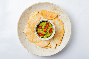 Fresh guacamole made from ripe avocados sits in a bowl surrounded by crunchy tortilla chips