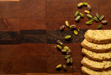 Batch of homemade pistachio biscotti surrounded by pistachio nuts and crumbs, with copy space