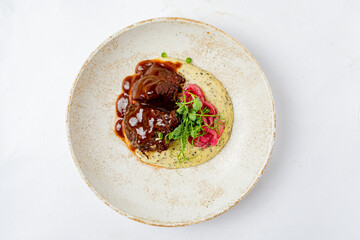 Savory beef stew sits atop smooth polenta, garnished with pickled vegetables for color and flavor