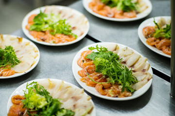 Plates display vibrant fish slices garnished with fresh greens, showcasing culinary artistry