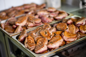 Grilled meat neatly arranged on trays, highlighting a bustling celebration kitchen scene
