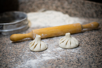 Two expertly shaped dumplings rest on a flour-dusted counter, ready for cooking