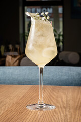 A tall glass filled with a light beverage sits on a wooden table, inviting relaxation