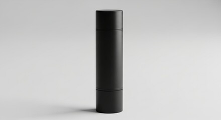 Matte black tube of lip balm featuring flat cap presented simply on smooth plain white background surface