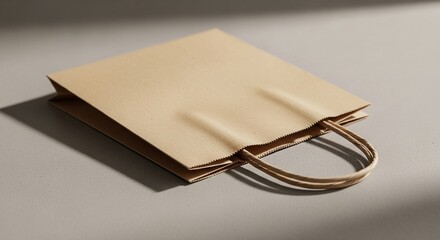 Folded craft paper bag with stylish twisted handles resting elegantly on smooth neutral textured surface
