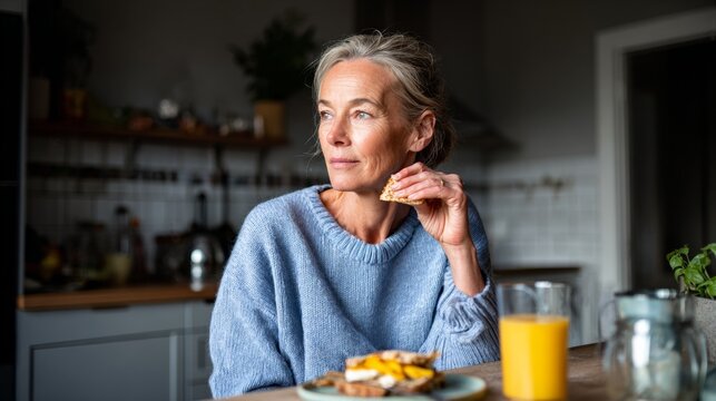 Woman sitting at kitchen table, enjoying breakfast.
