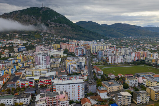 Aerial view of Lezhë with colourful residential blocks and Skanderbeg’s Tomb Peak rising above under cloudy skies. - Powered by Adobe