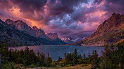 Wild goose island at sunrise with vibrant colorful clouds reflecting over calm lake surrounded by rugged mountain peaks in glacier national park montana dramatic scenic landscape