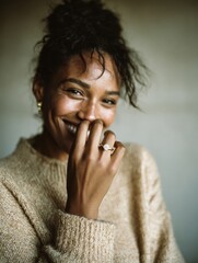 Happy mixed race woman with curly hair covering smile with hand displaying gold diamond ring on finger for engagement lifestyle advertisement