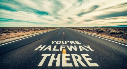 Road with motivational text YOU ARE HALFWAY THERE in bright sunlight