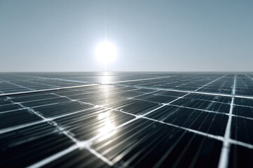 Close-up of a solar panel array reflecting sunlight under a bright sky, with the sun in the distance