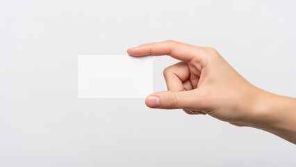 Fototapeta premium Hand holding a blank white business card against a light gray background