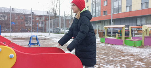 A girl prepares to catch her brother down a slide at a playground on a winter day.