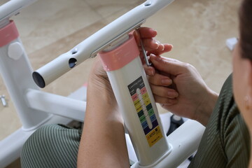 Female fingers tightening screws with hand tools and electric screwdriver on metal kids table and...