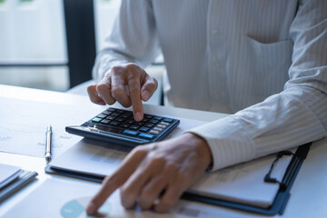 Male Professional Using Calculator for Business Budget Analysis.