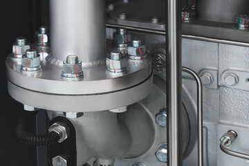 Part of a large industrial machine with large metal pipes as an industrial background.