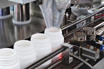 pharmaceutical industry, medicine pills are filling in the  bottle on production line machine conveyor at the medical factory. selective focus.
