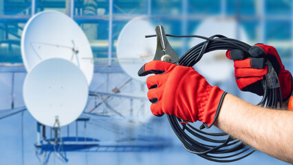 Satellite communication technician prepares signal cable with clamp tool, supporting installation...