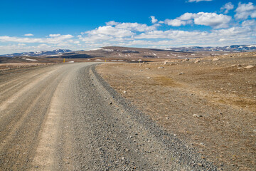 mountain road in an empty landscape in iceland at a sunny day