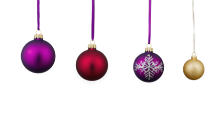 Colorful Christmas ornaments in various designs and sizes hanging on purple ribbons ready for holiday decoration