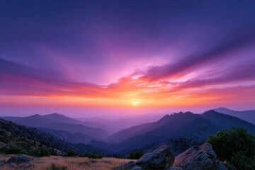 Obraz premium Sunset Symphony Over Mountains: The sky erupts in a mesmerizing dance of colors as the sun dips below the horizon, painting the mountain range with hues of purple, orange, and gold.