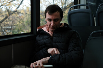 A man sits by the bus window and looks at his watch. The moment reflects routine commuting and the concept of daily scheduling.
