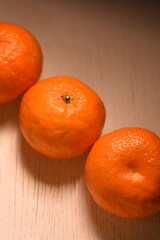 Close-up top view: three tangerines on a white table arranged diagonally.