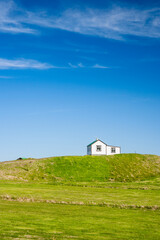 Obraz premium little house in iceland between a grenn meadow and the blue sky