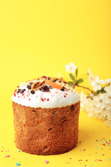 Traditional easter cakes with colorful sprinkles, with eggs and spring flowers on yellow background.