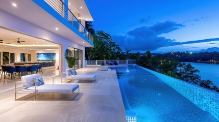 Fototapeta premium Modern luxury villa with infinity pool overlooking serene lake at twilight with beautiful blue sky and lush greenery