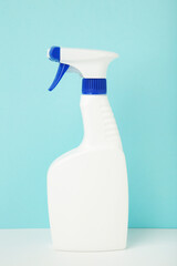 White spray bottle of cleaning product on blue background. Vertical photo